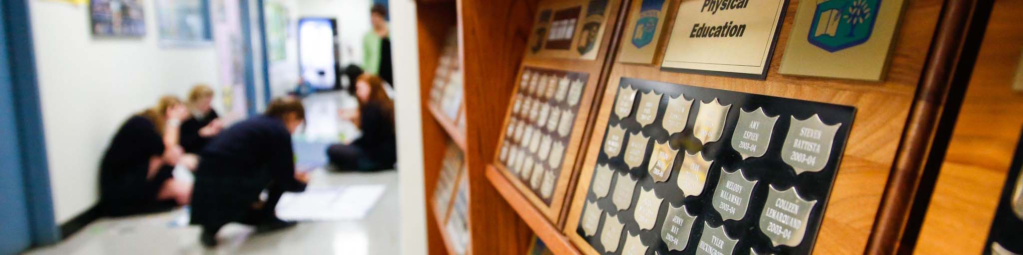 Awards & plaques cabinet and students working in the background